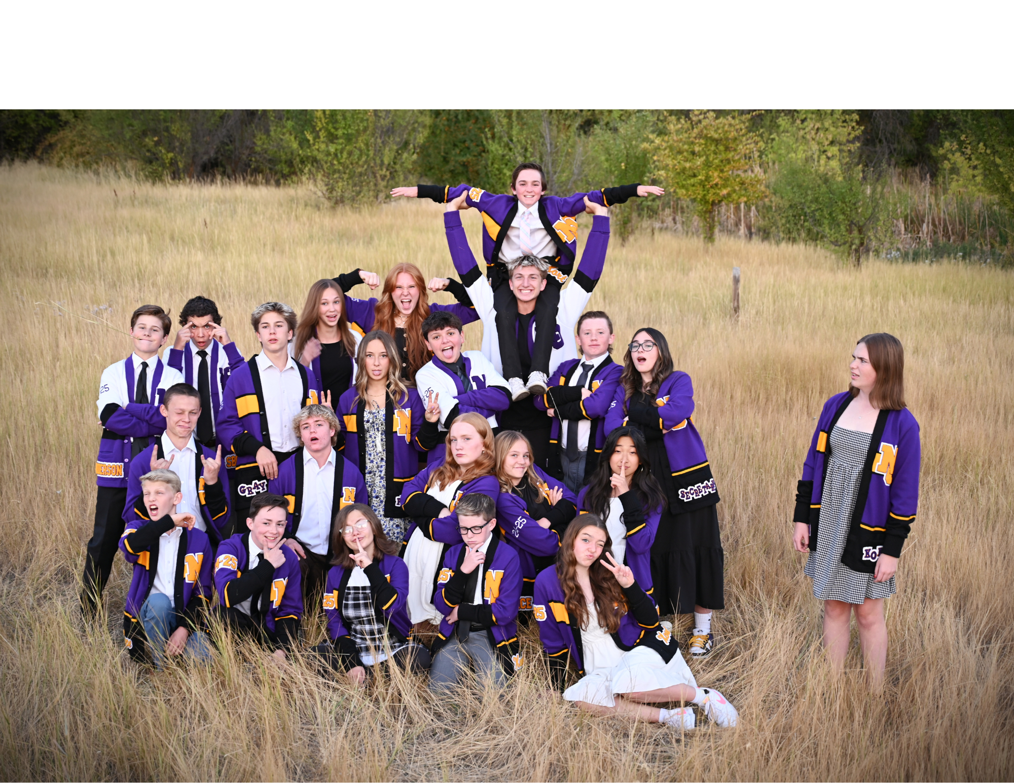 All officers standing in a field wiith white purple and gold jackets making a silly face