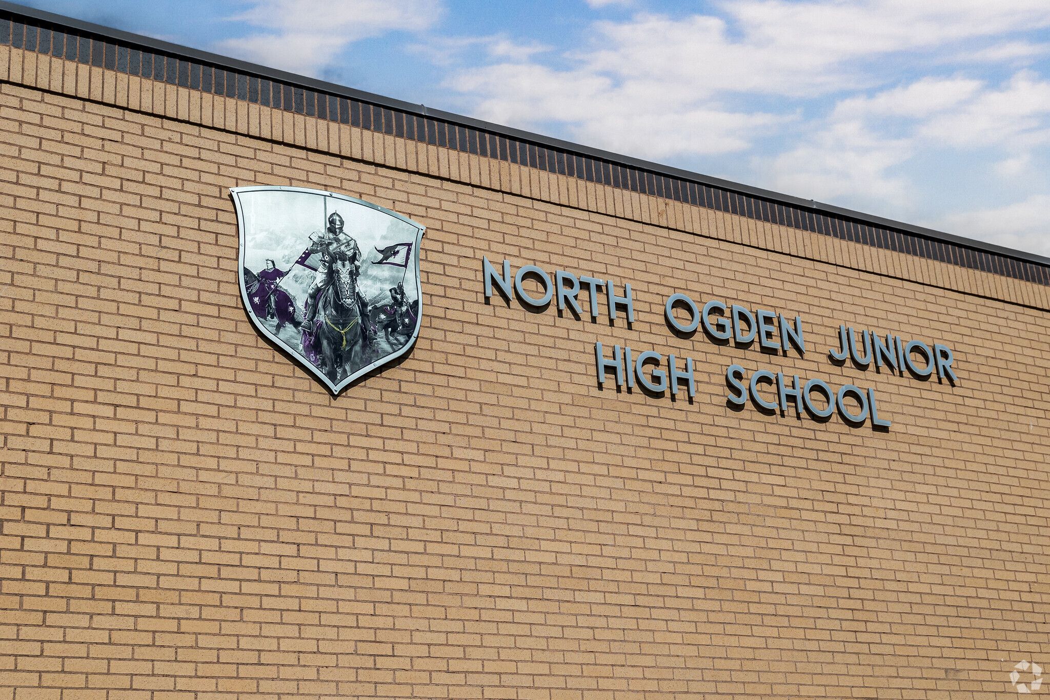 A sign on brck that reads north ogden jr high school with a shield and knight